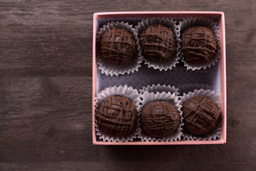Tasty chocolate candies in pink gift box on wooden background, close up