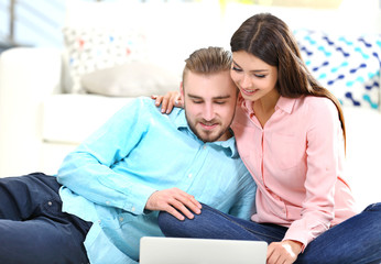 Happy couple sitting on the floor and working on laptop in a room