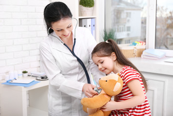 Doctor and child examining toy bear