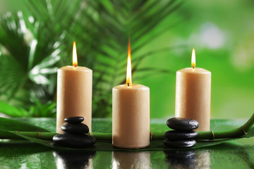 Fototapeta na wymiar Spa composition of candles, stones and bamboo on blurred background