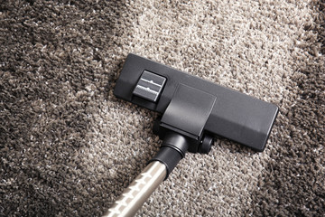 Cleaning concept - vacuum cleaner on grey soft carpet, close up