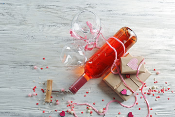 Fototapeta na wymiar Love concept - wine bottle with decorations on white wooden background, close up
