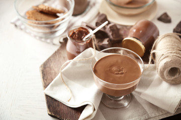 Melted chocolate on glass bowl, on wooden background