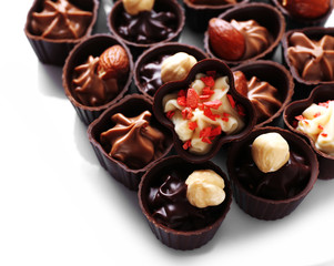 Delicious chocolate candies on white background, close up