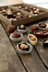 Different tasty chocolate candies on wooden table, close up