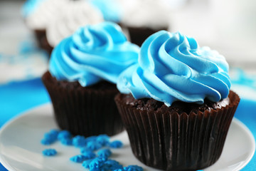 Delicious chocolate cupcakes with blue cream on decorated wooden  table, close up