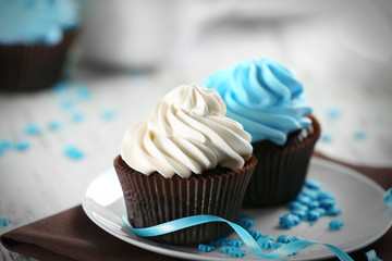 Chocolate cupcakes with colourful cream on decorated table , close up