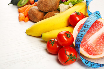 Fruits, vegetables and measuring tape on light wooden background. healthy eating concept.