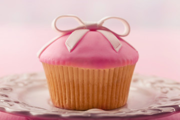 Tasty cupcake with bow on color wooden background