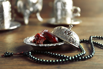 Dates fruit and rosary on served wooden background, close up