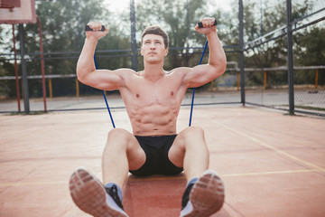strong athletic guy sports man stretches expander