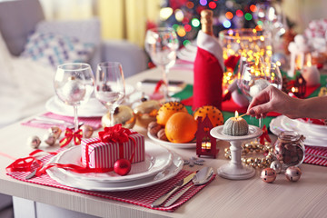 Woman hand lights a candle on holiday table setting