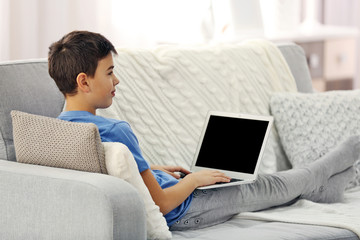 Boy with laptop sitting on a sofa