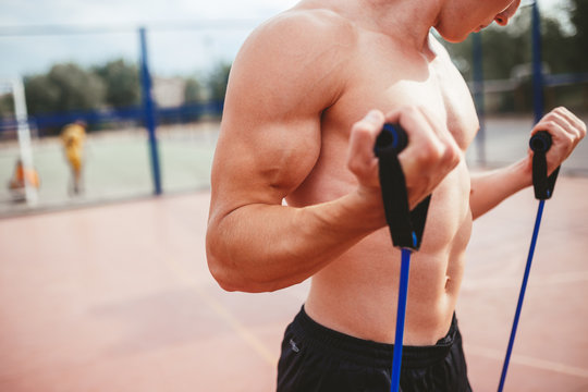 strong athletic guy sports man stretches expander
