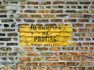 No dumping or posting sign on brick wall