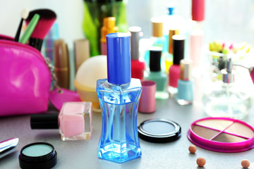 Perfume bottle with makeup tools and cosmetics on a table