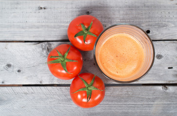 Tomato juice freshly pressed and tomatoes on a wooden table