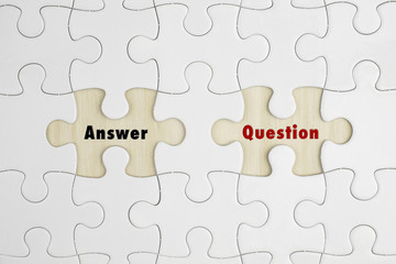Jigsaw puzzle on wood background with a word ANSWER and QUESTION