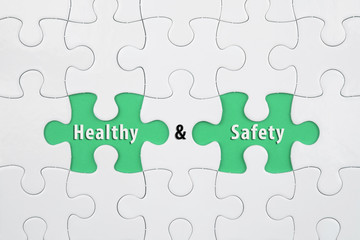 Jigsaw puzzle on color paper background with a word HEALTH and SAFETY