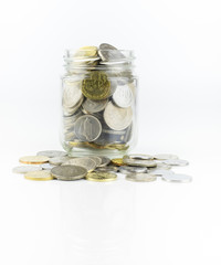 Glass jar with full of coins over white background