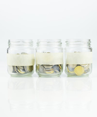 A empty label of glass jars with coins over white background