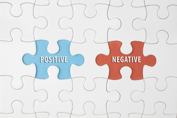 Fototapeta premium Jigsaw puzzle on color paper background with a word POSITIVE and NEGATIVE