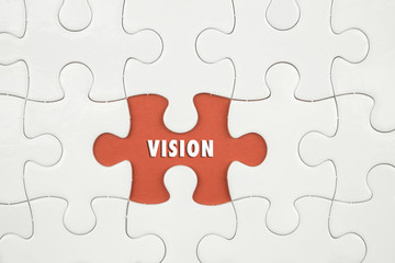 Jigsaw puzzle on color paper background with a word VISION