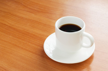 Fresh Black Coffee in a White Ceramic Cup on a Wooden Table