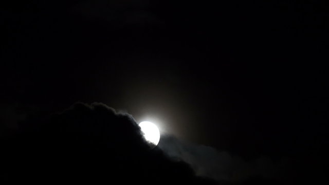Moon rising from behind night clouds.