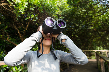 Woman use of the binoculars at forest