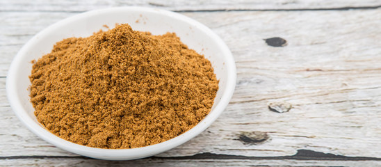 Garam masala or mix spices blend in white bowl over wooden background