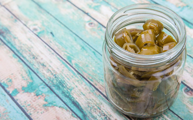 Pickled chili in mason jar over wooden background