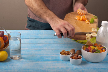 Man cooking at home preparing fruit salad