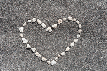 Stones in shape of heart on sand background