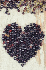 Vintage photo, Heart of fresh elderberry on old wooden background, symbol of love