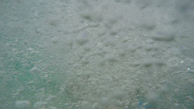 Couple jumping into caribbean water with camera