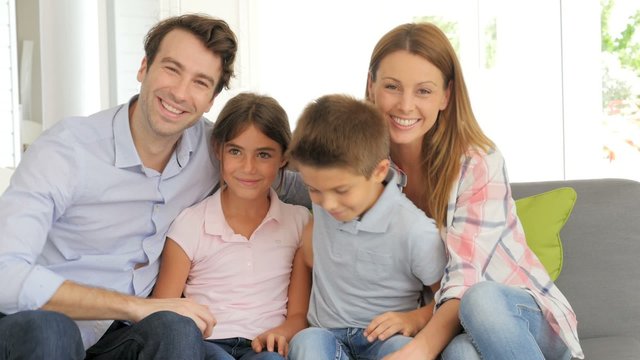 Cheerful family of four sitting in sofa