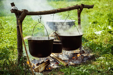 A group of cauldrons and kettle are hanged upon fire