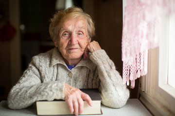 An old woman sits with a book.