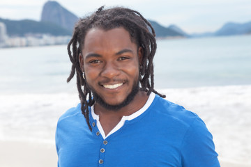 Sympathischer Mann mit Rastalocken am Strand in Rio