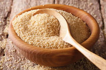 dry couscous in a wooden bowl close-up on the table. horizontal
