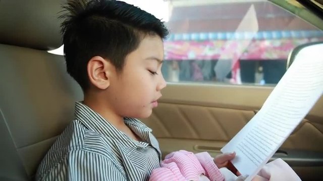 Little asian boy reading text in car