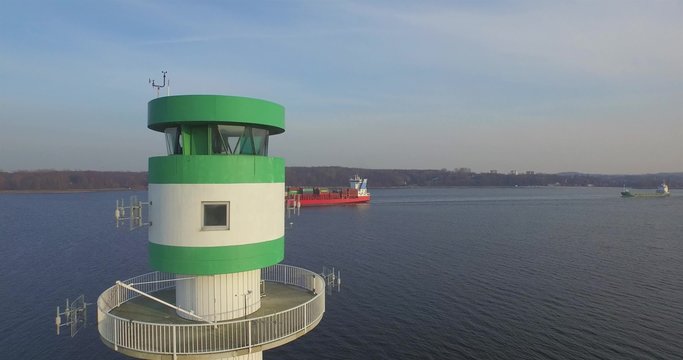 aerial view of  an lighthouse with an cargo vessel in background comming from the kiel canal