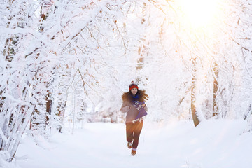 Naklejka na ściany i meble Girl running in winter park snow vacation