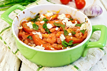Shrimp and tomatoes with feta in pan on board