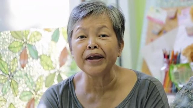 Happy asian senior woman smiling in front of camera.