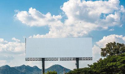 Blank billboard against white cloud and blue sky in forest