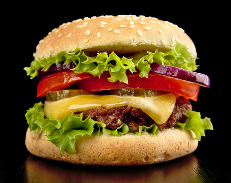 Big cheeseburger isolated on black background