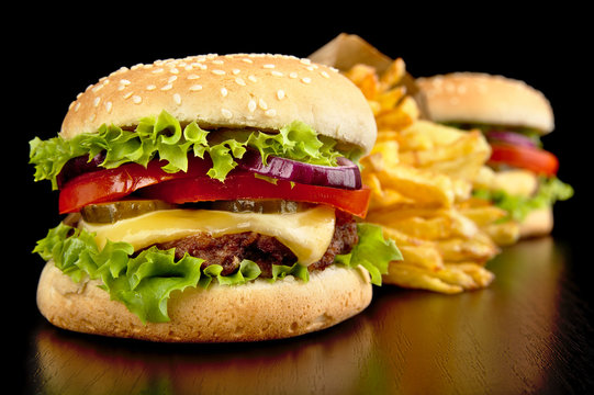 Big cheeseburgers with french fries on black board
