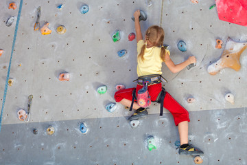 little girl climbing a rock wall - obrazy, fototapety, plakaty